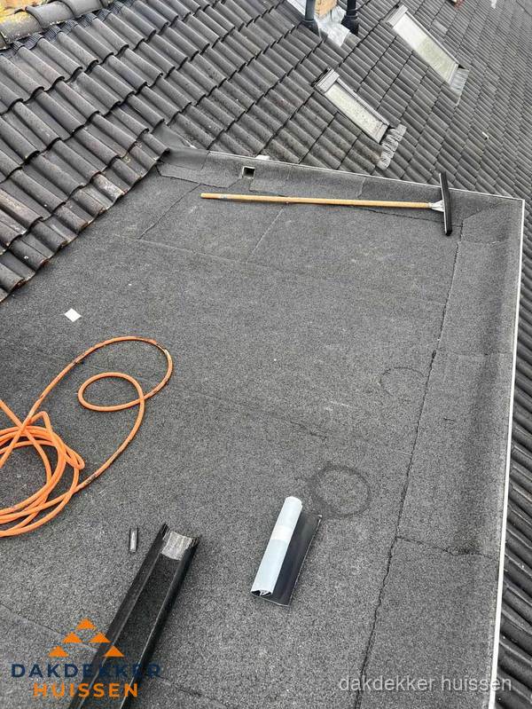 Plat dak reparatie met gereedschap en loodstroken in Huissen