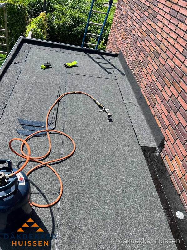 Plat dak met bitumen en brandgereedschap van dakdekkersbedrijf in Huissen