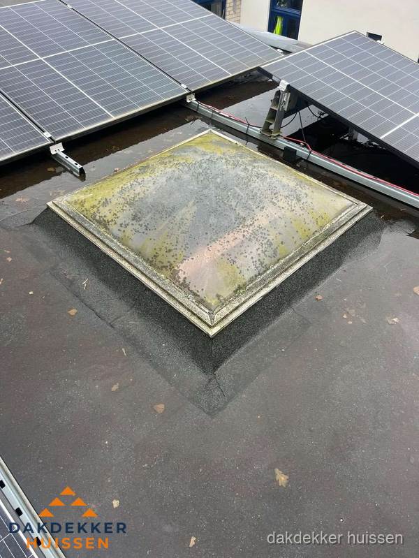 Vervuilde lichtkoepel op plat dak met zonnepanelen in Huissen