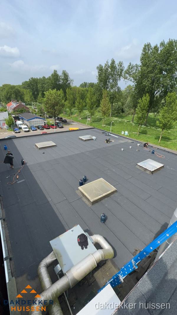 Dakdekker aan het werk op groot plat dak met bitumen in Huissen
