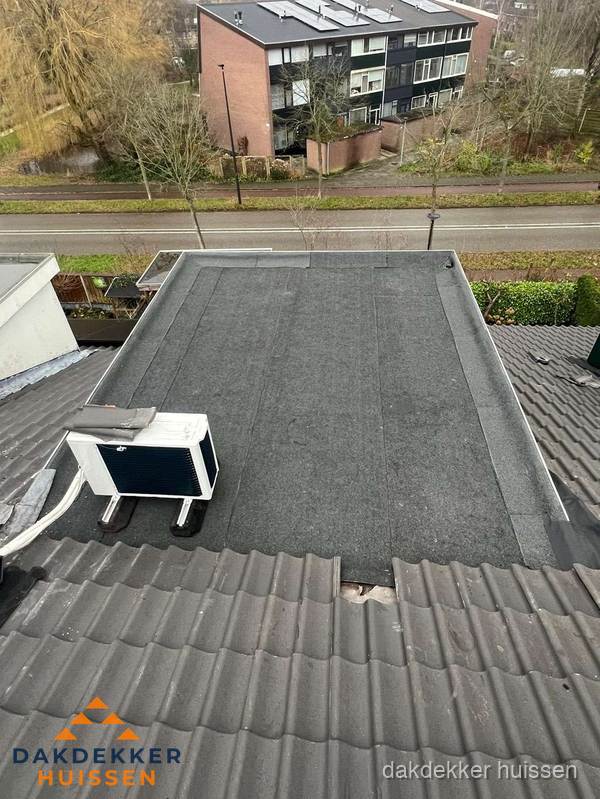 Plat dak inspectie met bitumen bedekking naast schuin pannendak in Huissen