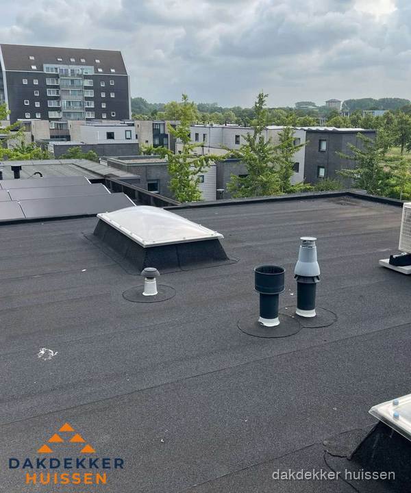 Groot plat dak met lichtkoepel en dakdoorvoeren in Huissen