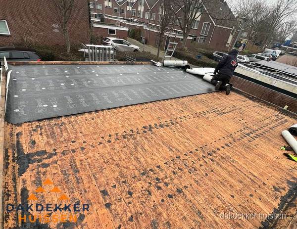 Dakdekker legt onderlaag op plat dak met houten constructie in Huissen