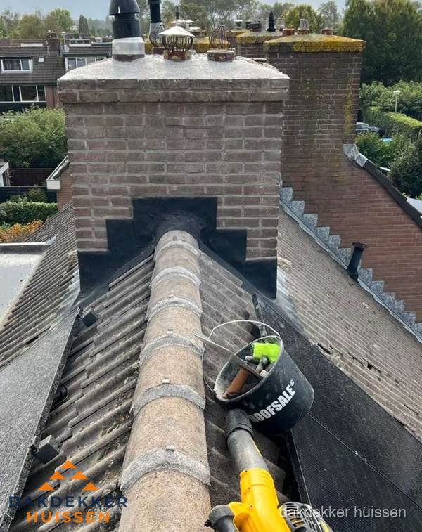 Schoorsteen met loodaansluiting en nokvorst op pannendak in Huissen