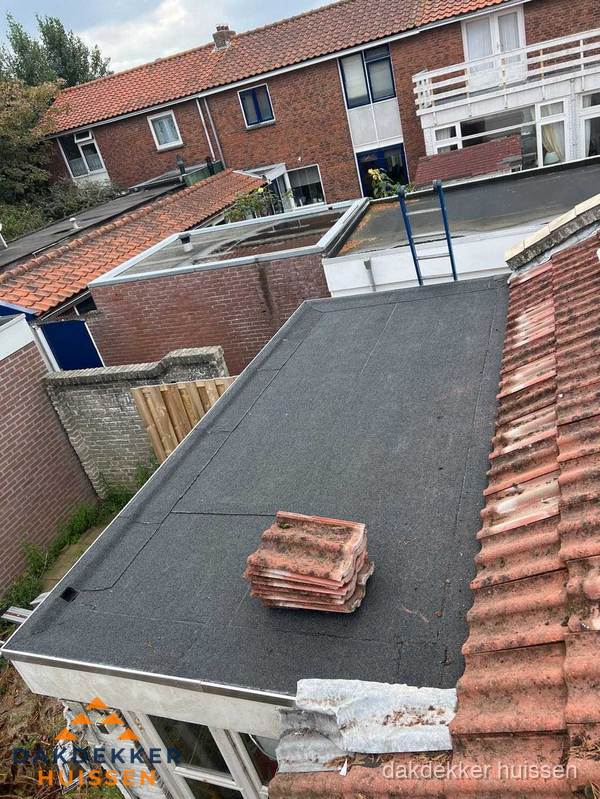 Plat dak aanbouw met bitumen naast schuin pannendak in Huissen